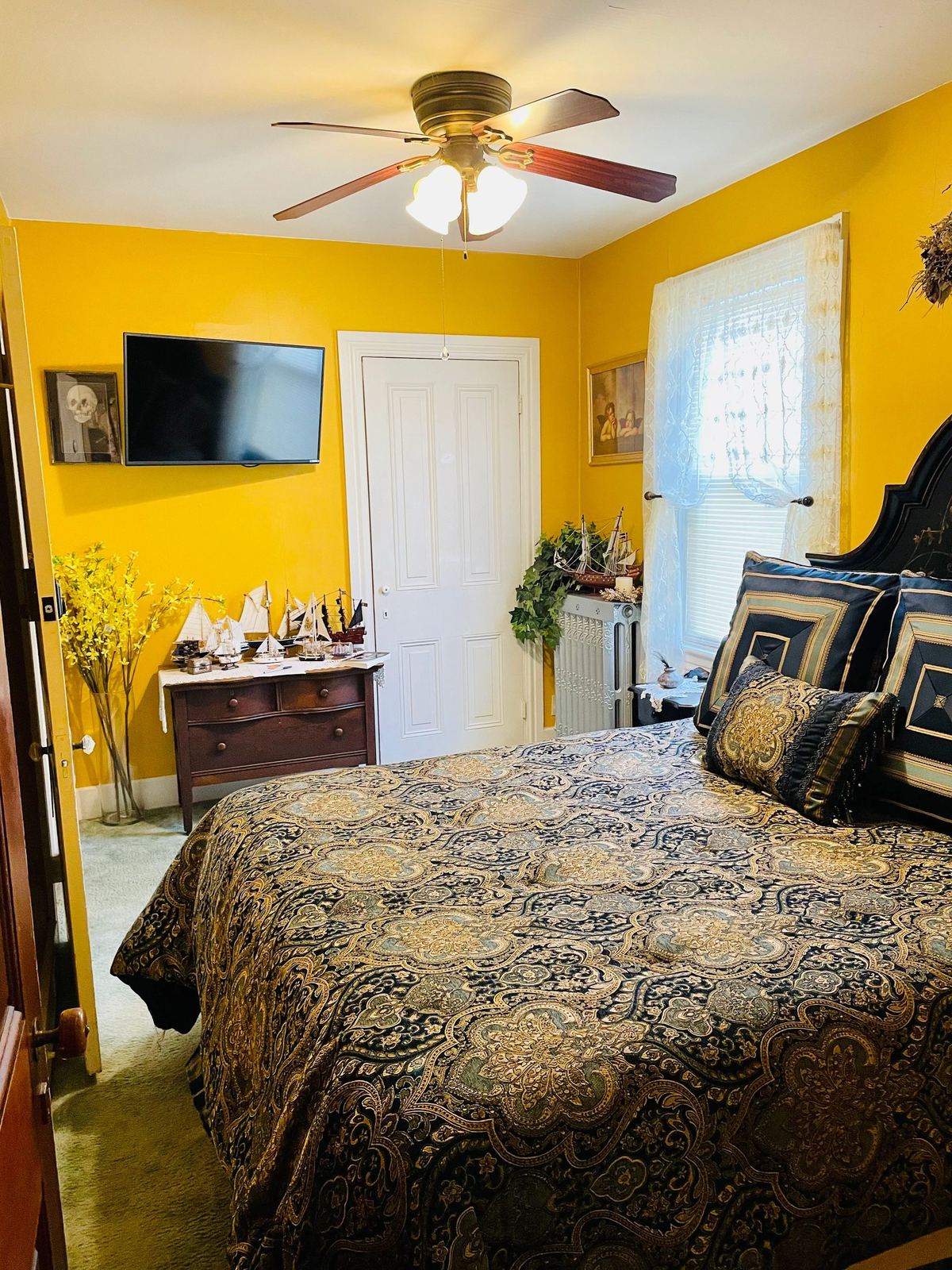 Angel Suite: golden walls, flat-screen TV, and a queen bed with dark paisley bedding